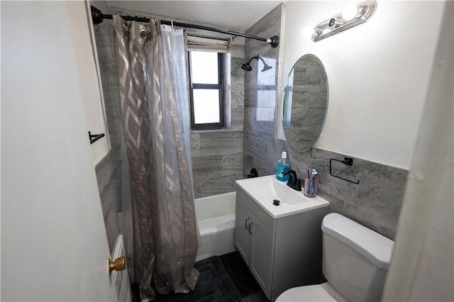 bathroom with vanity, toilet, tile walls, and shower / tub combo