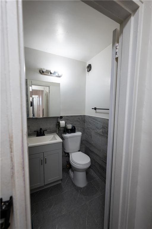 bathroom featuring vanity, wainscoting, tile walls, toilet, and tile patterned floors