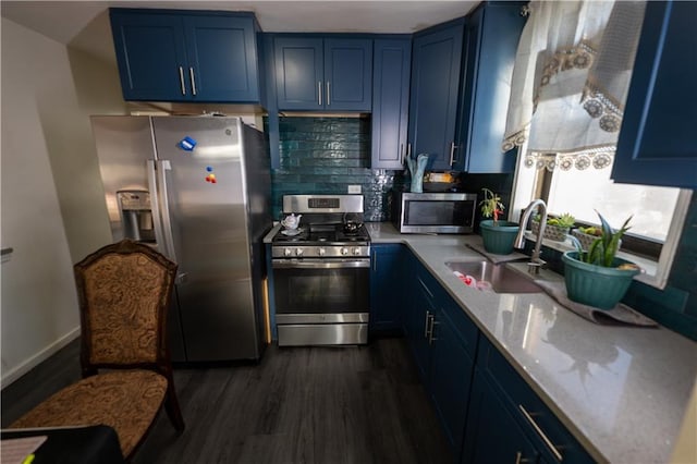 kitchen with dark wood-type flooring, blue cabinetry, appliances with stainless steel finishes, and a sink