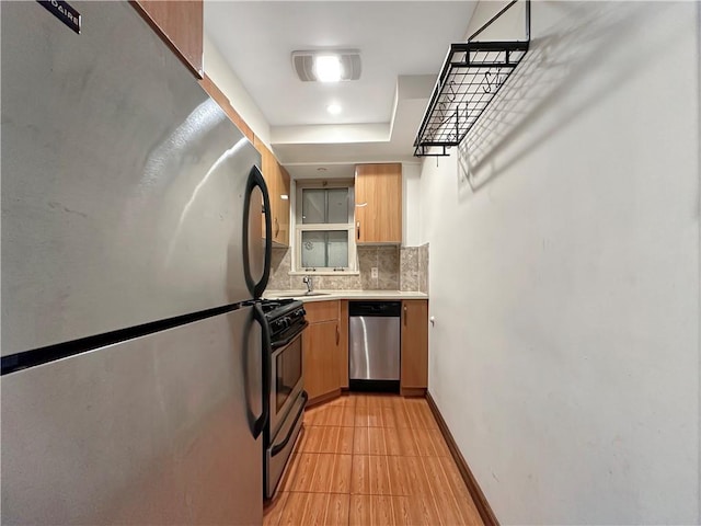 kitchen with light tile patterned flooring, tasteful backsplash, a raised ceiling, sink, and stainless steel appliances