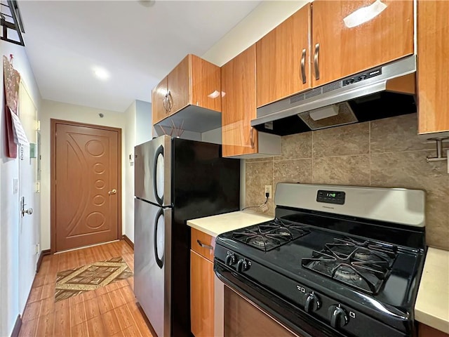 kitchen featuring backsplash, gas range, and stainless steel fridge