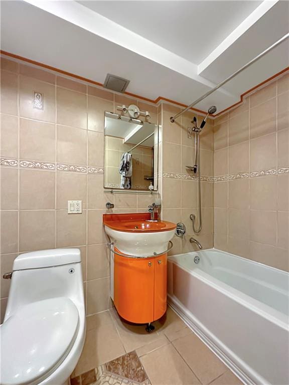 full bathroom featuring tile patterned floors, toilet, tile walls, vanity, and tiled shower / bath combo