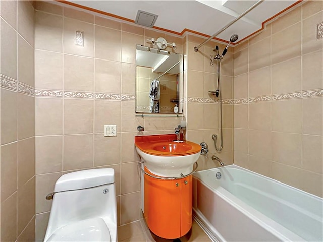 full bathroom with tile walls, decorative backsplash, tiled shower / bath combo, vanity, and toilet