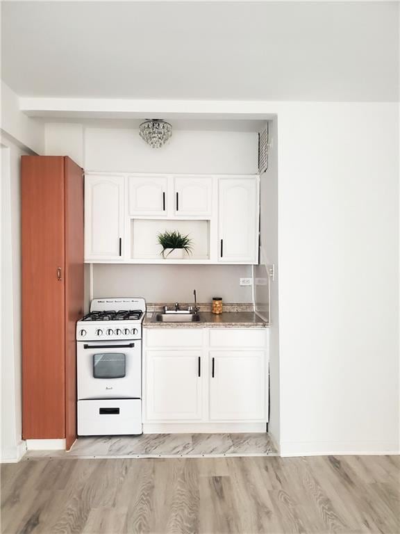 bar with white cabinetry, white range with gas cooktop, sink, and light wood-type flooring