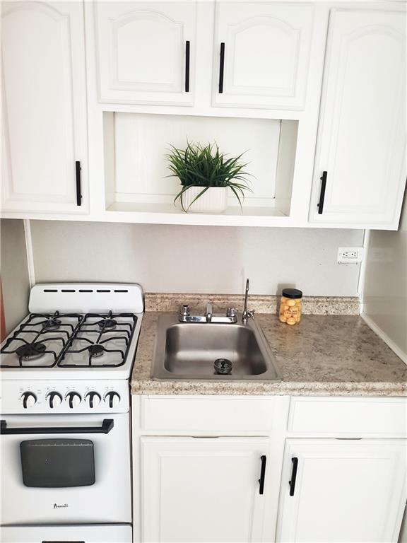 kitchen featuring white cabinetry, sink, and white gas range oven