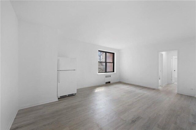 unfurnished room with radiator and light hardwood / wood-style flooring