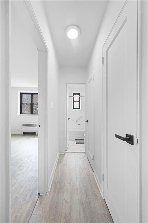 corridor featuring radiator and light hardwood / wood-style flooring