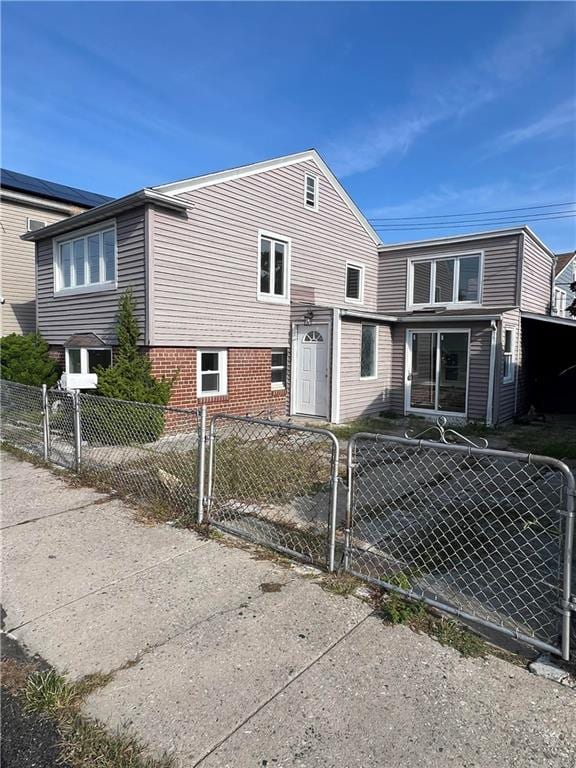 view of front of property featuring a fenced front yard, brick siding, and a gate