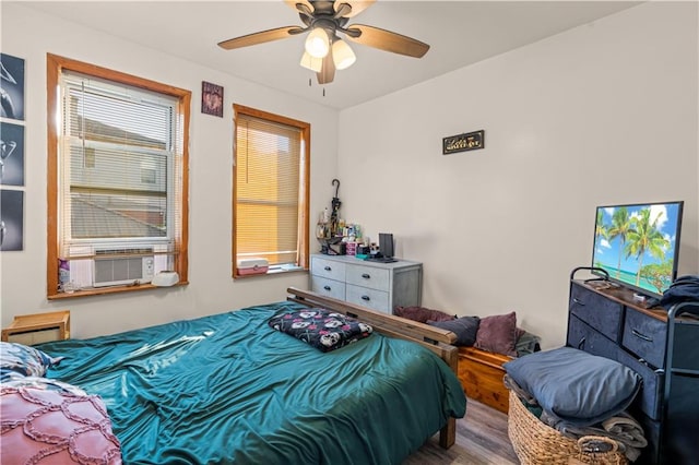 bedroom featuring cooling unit, hardwood / wood-style flooring, and ceiling fan