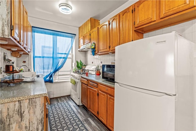 kitchen with dark wood-type flooring, sink, backsplash, and white appliances