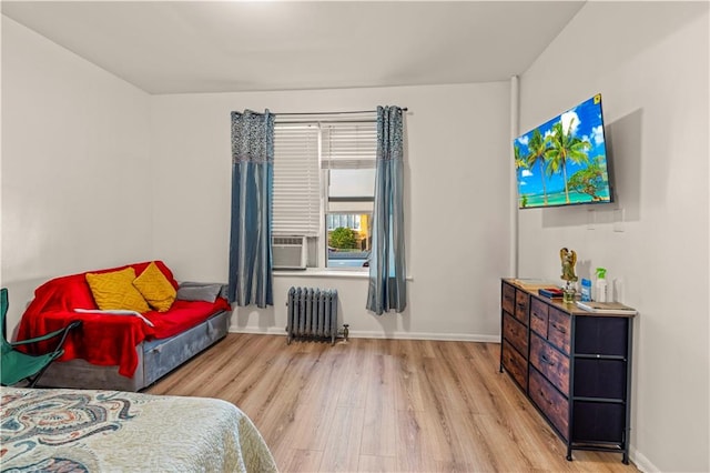 bedroom with radiator, cooling unit, and light wood-type flooring