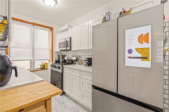 kitchen featuring tasteful backsplash, white cabinets, and appliances with stainless steel finishes