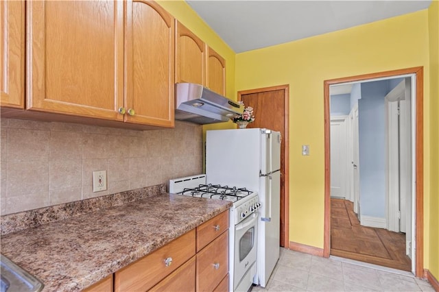 kitchen featuring light stone countertops, white range with gas cooktop, light tile patterned floors, and backsplash