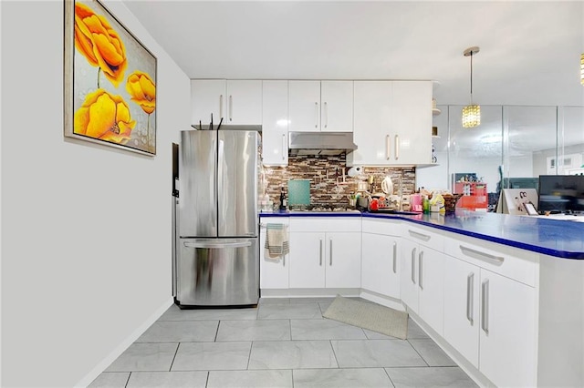 kitchen featuring white cabinets, pendant lighting, backsplash, and stainless steel refrigerator