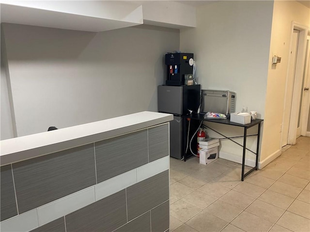 interior space with light tile patterned floors and stainless steel refrigerator