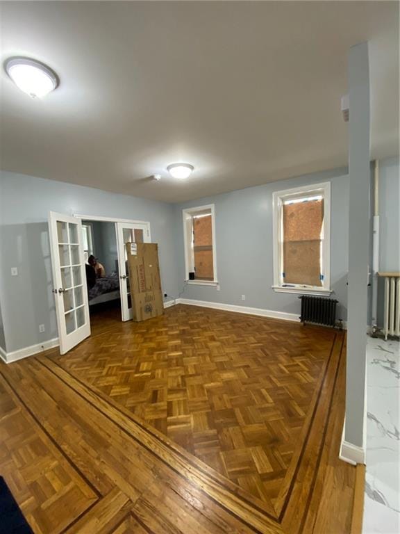 unfurnished room with parquet floors, radiator, and french doors