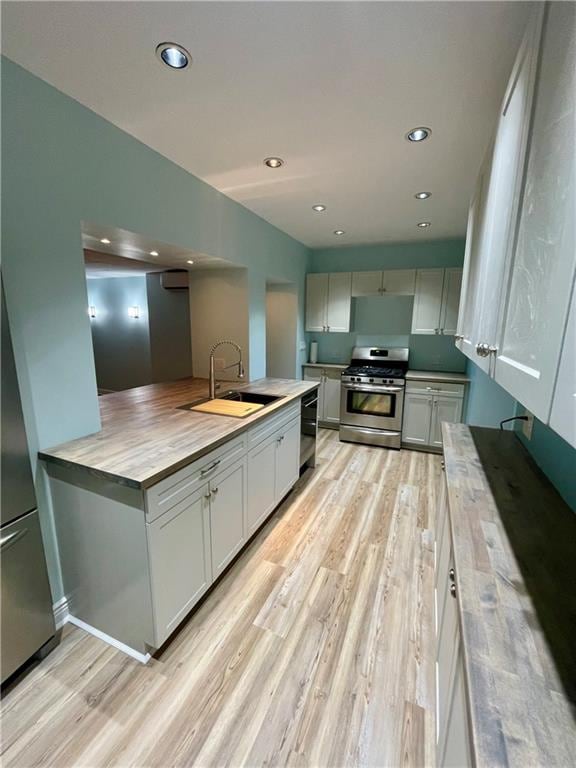 kitchen featuring light wood-style flooring, a sink, recessed lighting, stainless steel range with gas cooktop, and dishwasher