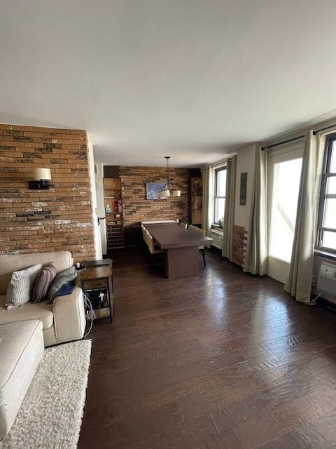 living room with dark hardwood / wood-style floors and brick wall