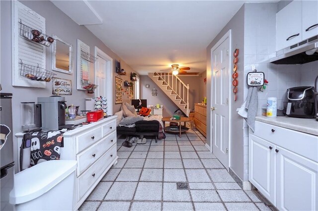 kitchen with ceiling fan, white cabinets, and backsplash