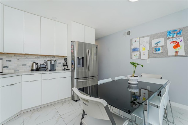 kitchen with backsplash, stainless steel fridge with ice dispenser, and white cabinets