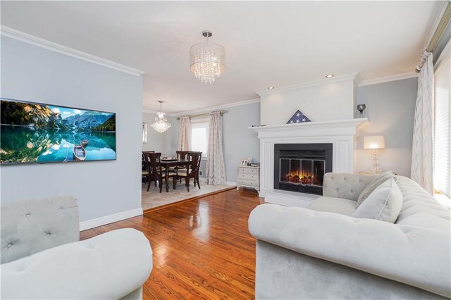 living room with ornamental molding, hardwood / wood-style floors, and a notable chandelier