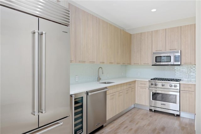 kitchen with high quality appliances, light countertops, a sink, and light brown cabinetry