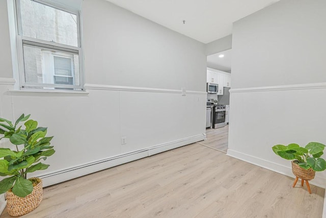 unfurnished room with a baseboard radiator and light wood-style floors