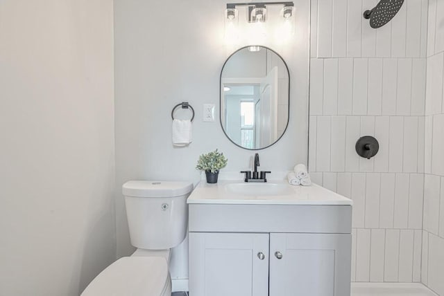 bathroom featuring tiled shower, toilet, and vanity