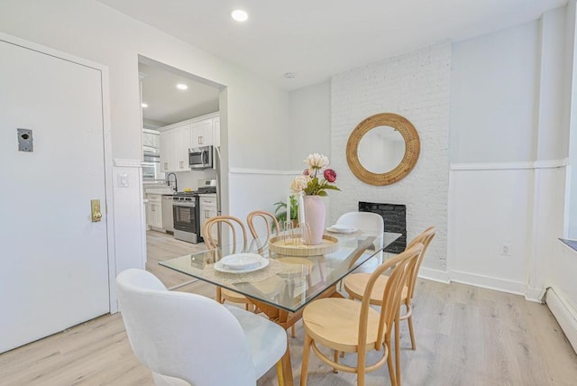 dining room with a fireplace, light wood-type flooring, and baseboard heating