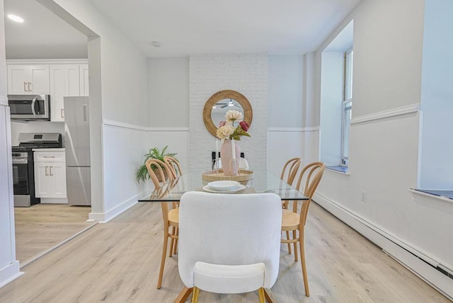 dining room with a baseboard heating unit, baseboards, and light wood-type flooring