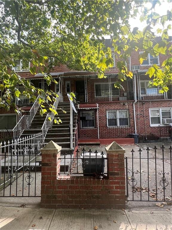 multi unit property featuring a fenced front yard, a gate, and brick siding