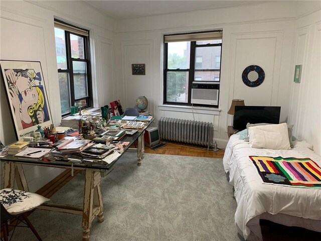 bedroom with multiple windows, radiator heating unit, and cooling unit