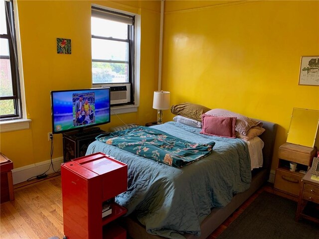 bedroom with hardwood / wood-style flooring and multiple windows