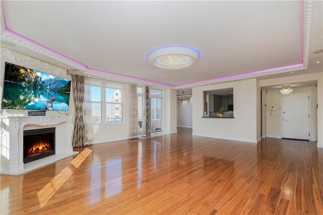 unfurnished living room with a tray ceiling, wood-type flooring, and a premium fireplace