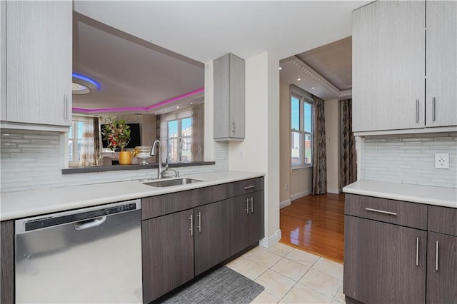 kitchen featuring baseboards, dishwasher, light countertops, light tile patterned flooring, and a sink