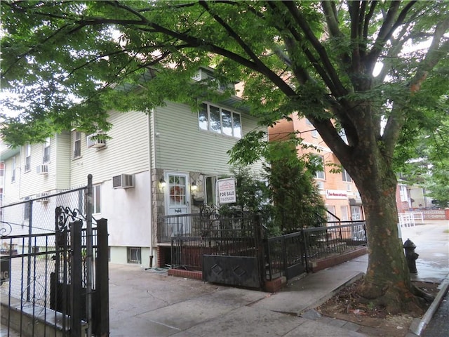 view of front of house featuring an AC wall unit, a gate, and a fenced front yard