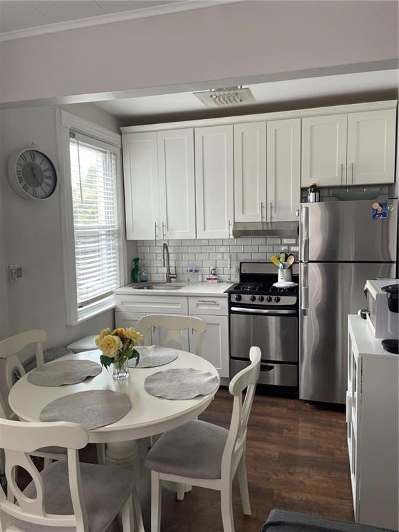 kitchen featuring decorative backsplash, stainless steel appliances, white cabinetry, and sink