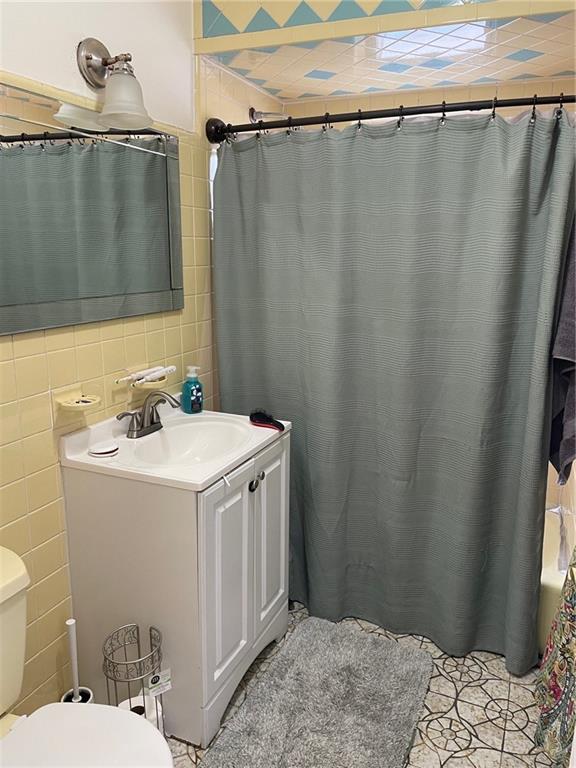 full bathroom with vanity, toilet, tile walls, and shower / tub combo