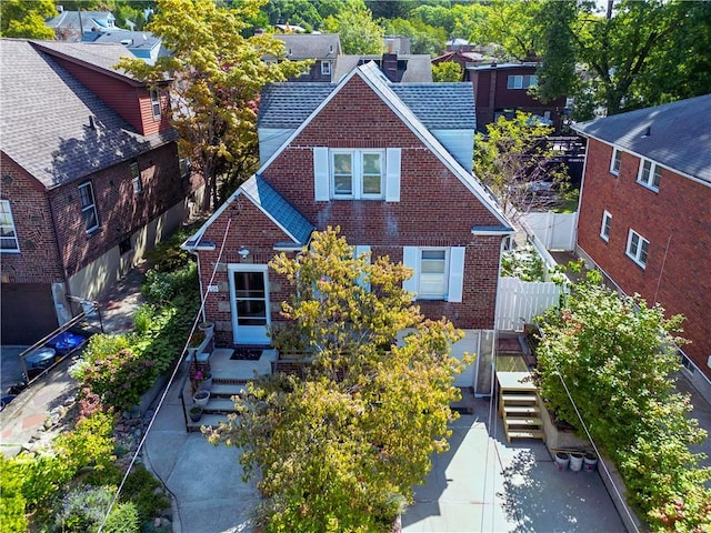 view of front of house featuring roof with shingles, a chimney, fence, and brick siding