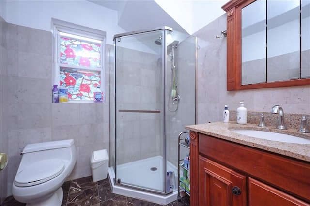 bathroom with a shower stall, tile walls, toilet, marble finish floor, and vanity