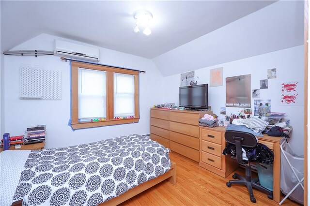 bedroom with vaulted ceiling, a wall unit AC, and light wood-type flooring