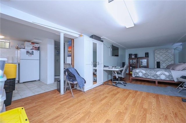 bedroom with light wood finished floors and freestanding refrigerator