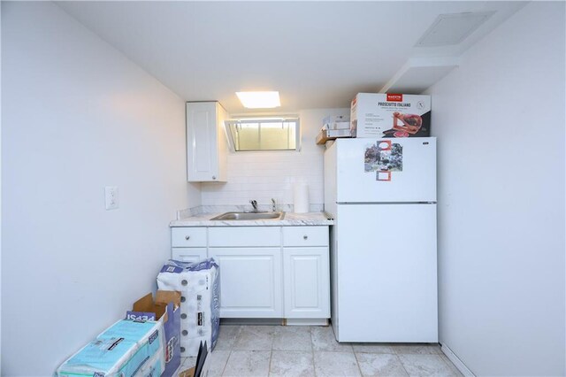 kitchen featuring white cabinetry, sink, white fridge, and backsplash