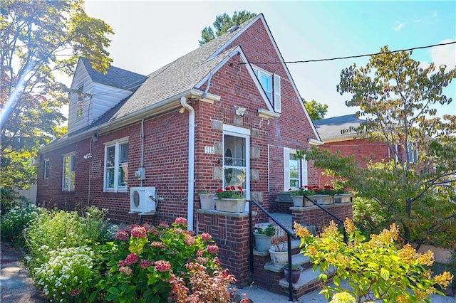 view of property exterior featuring brick siding and a shingled roof