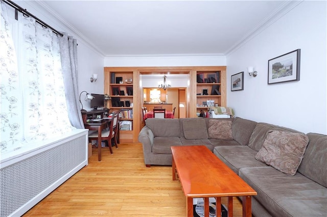 living room with built in features, radiator heating unit, an inviting chandelier, crown molding, and light wood finished floors