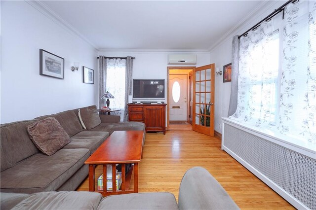 living room with radiator heating unit, crown molding, light hardwood / wood-style flooring, and a wall mounted AC