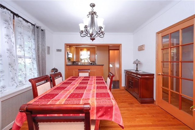 dining space featuring light wood-style flooring, radiator, and an inviting chandelier