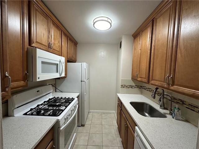 kitchen with sink, white appliances, backsplash, light stone countertops, and light tile patterned flooring