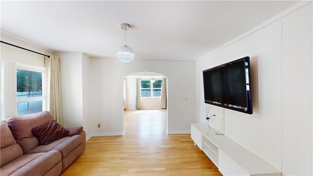 living room with arched walkways, light wood finished floors, and baseboards