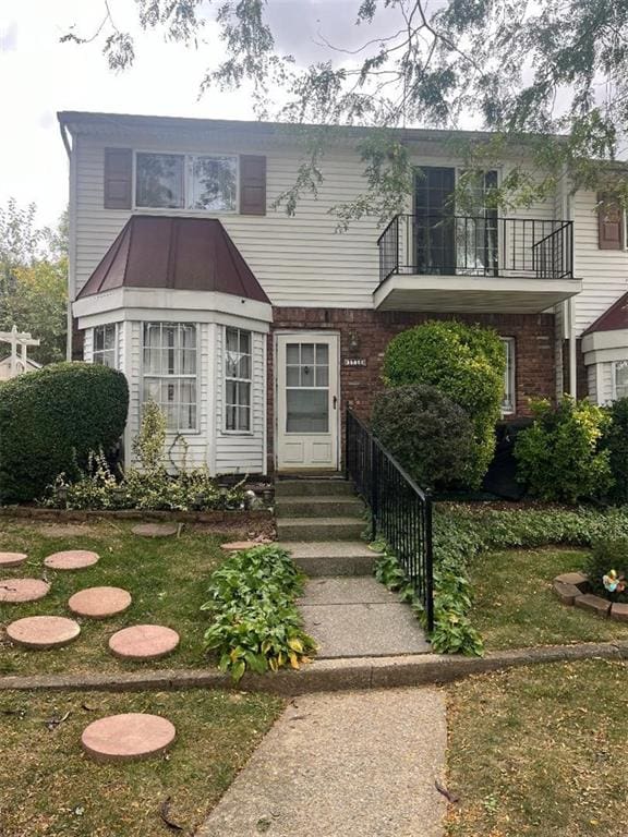 view of front of property with a front yard and a balcony